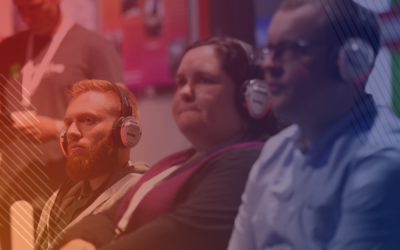 Three delegates watching a speaker at Tech Show North wearing headphones