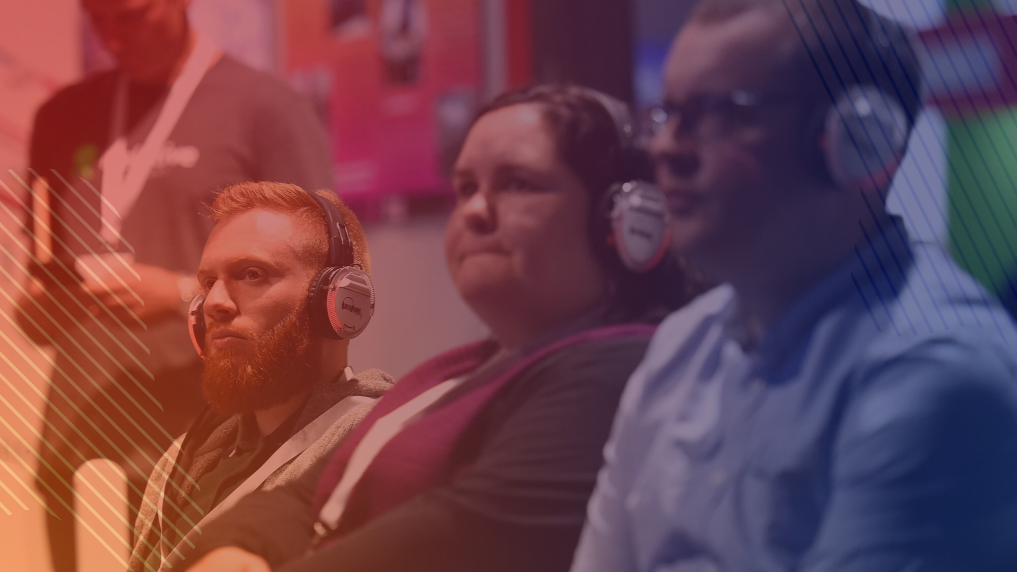 Three delegates watching a speaker at Tech Show North wearing headphones