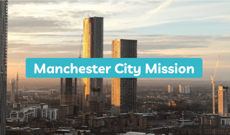 Manchester City Mission logo above a photo of the city's skyscrapers