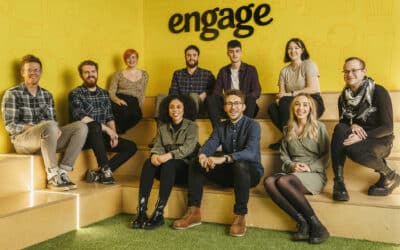 New recruits at Engage - a team of 10 sits in front of a yellow wall