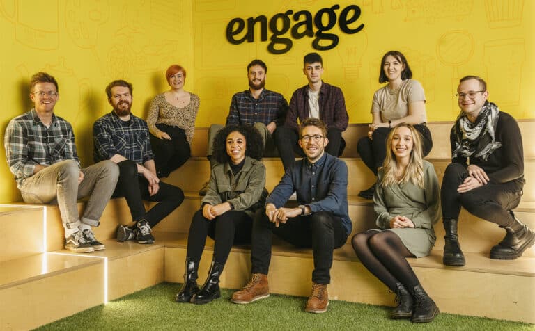 New recruits at Engage - a team of 10 sits in front of a yellow wall